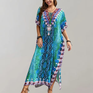 
A woman wearing a bohemian ethnic print kaftan in aqua blue, featuring a maxi dress design suitable for beachwear. She is smiling and showcasing the one-size garment with a relaxed fit, which highlights the dress's colorful patterns and flowing sleeves. The dress has a round neckline and falls gracefully to her waist, combining elements of casual elegance and vibrant fashion design.