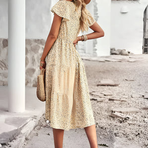 A woman wearing a Bohemian floral midi dress with puffed sleeves, standing and posing.