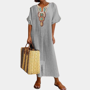 
A light grey bohemian maxi dress featuring intricate ethnic embroidery, designed with long sleeves and a flowing silhouette. The dress is styled with a collar and has a relaxed, elegant fit suitable for a 3XL size.