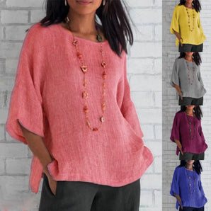 
A woman wearing a Bohemian oversized linen tunic, featuring a casual summer blouse style in a light pink color. The blouse has a relaxed fit with flowing sleeves and a round neckline, showcasing a fashionable and comfortable design suitable for warm weather.