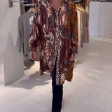 Bohemian silk blouse with an intricate designer print, featuring stylish bell sleeves. The blouse showcases vibrant colors, including magenta and electric blue, suitable for formal wear or events.