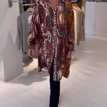 Bohemian silk blouse with an intricate designer print, featuring stylish bell sleeves. The blouse showcases vibrant colors, including magenta and electric blue, suitable for formal wear or events.