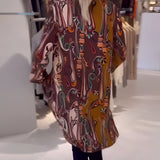 Bohemian silk blouse with designer printed pattern, featuring bell sleeves, displayed on a mannequin, accessorized with a necklace.