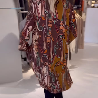 Bohemian silk blouse with designer printed pattern, featuring bell sleeves, displayed on a mannequin, accessorized with a necklace.