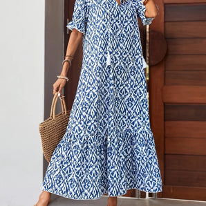 Blue boho maxi dress with a V-neck, featuring an ethnic pattern design, suitable for summer beachwear. The dress includes sleeves and a defined waist, embodying a casual yet stylish look.