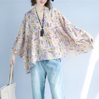 
A women's boho chic blouse with a v-neck design featuring a leaf pattern, wide sleeves, and a fashionable, elegant look. The blouse is predominantly white, highlighting its stylish and versatile nature.
