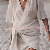 Boho-Chic V-Neck Mini Dress worn by a woman with sunglasses, featuring a loose-fitting design with short sleeves, cinched waist, and flowing fabric perfect for summer or as a beach cover-up.