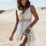 Boho chic white lace maxi dress with long sleeves and a fitted waist, worn by a woman with long hair against a clear sky backdrop, ideal for a summer beach wedding.
