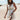 Boho chic white lace maxi dress with long sleeves and a fitted waist, worn by a woman with long hair against a clear sky backdrop, ideal for a summer beach wedding.