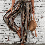 Boho Women's Tribal Print Wide Leg Festival Pants worn by a person, showcasing a colorful tribal pattern and a relaxed wide-leg fit. The image captures parts of the person's legs and hints at a casual, bohemian style suitable for festivals.