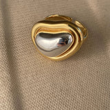 Bold gold adjustable statement ring with large reflective gemstone, close-up view showing intricate details and shimmering surface.