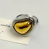 Bold gold adjustable statement ring featuring a large reflective amber heart-shaped gemstone.