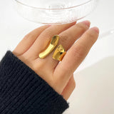 A woman's hand wearing a modern, sculptural bold gold statement ring on her finger.