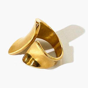 A modern, sculptural gold statement ring made of metal, designed as a bold fashion accessory.
