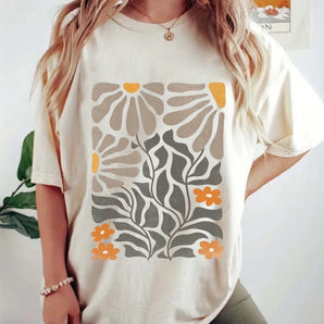 Women's botanical print t-shirt in white, sized 3XL, featuring a floral design with orange accents. The tee has short sleeves and is styled for a cool, neutral summer fashion look.