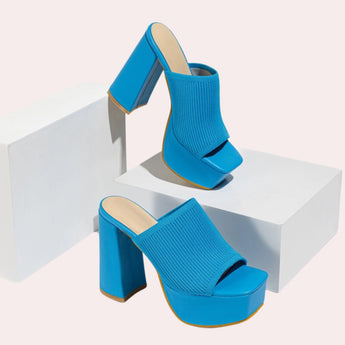 Bright orange ankle boots with a stretch fit sock design, featuring neon details, paired with blue jeans.