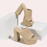 Bright orange ankle boots with a stretch fit sock design and neon detail, displayed on a khaki background. The boots feature a high heel, showcasing a stylish and modern appearance.