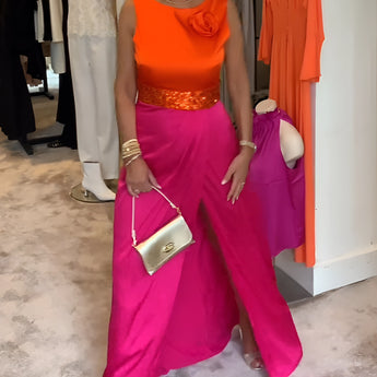 Bright pink palazzo pants paired with an orange silk blouse, featuring a chic summer outfit displayed on a mannequin.