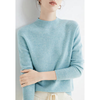Woman wearing a bright red cashmere crew neck sweater, paired with jeans, showcasing winter fashion pullover in an outdoor setting.