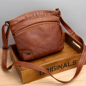 Brown leather crossbody bag for women featuring zipper pockets, adjustable strap, and elegant design.
