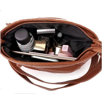 Brown leather crossbody bag for women featuring zipper pockets, with a sleek and stylish design.