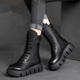 Black leather high-top military combat boots shown on a person's feet, emphasizing the durable leather material and stylish design.