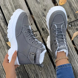 Brown platform chunky lace-up ankle boots worn by a person, featuring a sturdy design suitable for hiking, with visible socks and a background of natural outdoor elements.