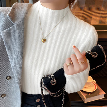 
A woman wearing a brown ribbed sweater that appears cozy and stylish for fall, paired with gold earrings. The sweater has a beige hue and features long sleeves, a high neck, and a fitted design, emphasizing the shoulders. The woman is captured with a gentle gesture, highlighting the elegance of the outfit.