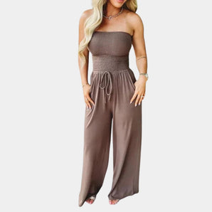 
A brown strapless wide-leg jumpsuit designed as a chic summer outfit, displayed in a 3XL size. The jumpsuit features a strapless and sleeveless design, highlighting the arms and neck, with a fitted waist and flowing wide-leg pants.