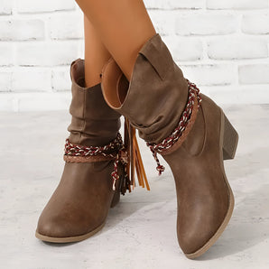 Brown suede ankle boots featuring a tassel and braided strap design in a boho chic style.