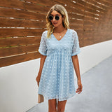 
A woman wearing a blue floral mini dress poses outdoors. The dress is lightweight, ideal for summer fashion, and styled in a one-piece garment. She accessorizes with sunglasses that add a fashionable touch to her look.