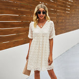 
A woman wearing a burgundy floral mini dress with beige accents, styled for summer fashion. The dress is lightweight and features short sleeves, highlighting the shoulders and waist. She is smiling and accessorized with sunglasses, adding a playful touch to her outdoor look.
