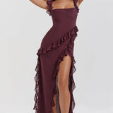 A woman wearing a burgundy off-shoulder ruffle maxi dress made of chiffon, featuring an elegant asymmetric design. The dress is sleeveless with a fitted waist, showcasing a stylish and flowing silhouette suitable for formal occasions.