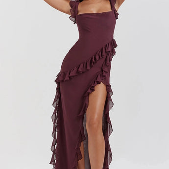 A woman wearing a burgundy off-shoulder ruffle maxi dress made of chiffon, featuring an elegant asymmetric design. The dress is sleeveless with a fitted waist, showcasing a stylish and flowing silhouette suitable for formal occasions.