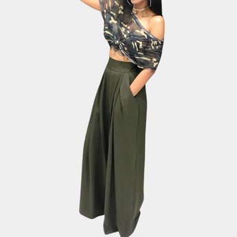 A woman wearing a light green, high-waisted, wide-leg palazzo pants with a sleeveless top, showcasing the flowy design and elegant fit of the pants.