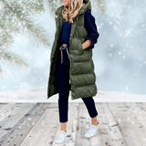 
A woman standing outdoors wearing a green long puffer coat with a detachable hood. The coat features a sleek design with long sleeves and a defined waistline. She appears happy and the coat provides a stylish, warm appearance suitable for cold weather.