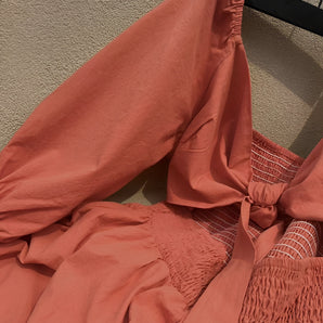 Burnt orange lightweight pants with a smocked waist and elastic cuffs, featuring a soft fabric texture.