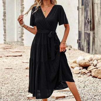 Black burnt orange midi dress with a ruffle skirt and flutter sleeves, modeled by a person wearing sunglasses with black hair.