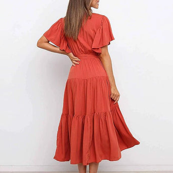 Burnt orange midi dress featuring a ruffle skirt and flutter sleeves, modeled by a person with visible hair and part of their leg showing. The dress has a fitted waist and a flattering neckline.
