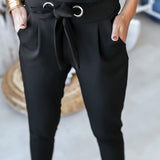 
A woman wearing black tie-waist paperbag trousers, designed with a casual chic comfort fit, emphasizing the waist and a relaxed thigh area.