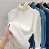 
A soft and luxurious cashmere turtleneck sweater in a light grey color, elegantly hanging on a clothes hanger, showcasing its long sleeves and high neck design.