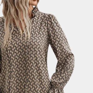 Women's chain-link print long sleeve blouse with a geometric pattern, featuring a collared neckline and button-up design. The blouse is styled with a grey color scheme and paired with a leather jacket and blazer.