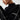 A woman wearing a chic black cut-out sweater, showcasing designer knitwear with a focus on the shoulders and neckline.