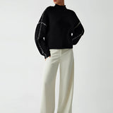 Chic black cut-out sweater for women, featuring a stylish designer knitwear design with distinct cut-outs around the shoulders and neck area, showcasing the upper arms and collarbone area. The long sleeves and slim fit accentuate the waist, offering a modern and elegant look.