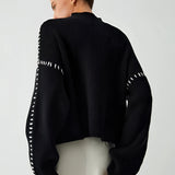 A chic black cut-out sweater featuring a stylish design, highlighting key areas such as shoulders and neck, with detailed sleeves and a fitted waist. The sweater exemplifies modern women's designer knitwear.