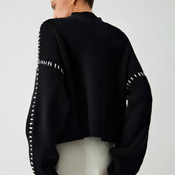 A chic black cut-out sweater featuring a stylish design, highlighting key areas such as shoulders and neck, with detailed sleeves and a fitted waist. The sweater exemplifies modern women's designer knitwear.