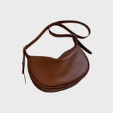 Chic brown leather designer saddle bag with a luxury equestrian crossbody style, featuring a curved silhouette and adjustable shoulder strap.