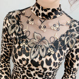 Chic high neck leopard print blouse featuring a stylish black and white pattern, back button detail, and long sleeves, highlighting contemporary fashion design.