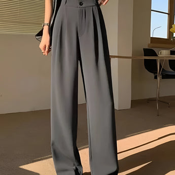 Chic urban women's fashion featuring a model wearing gray wide-leg trousers, a cropped tank top, and a cardigan in size 2XL; posed in front of a window.