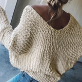 
A woman wearing a chunky knit off-shoulder beige sweater paired with jeans, showcasing a cozy and stylish look for winter fashion. The sweater features long sleeves and a relaxed fit, highlighting its comfortable and trendy design.